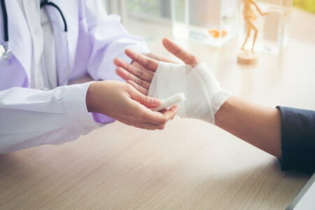 Doctor wrapping a man’s hand with a white bandage.