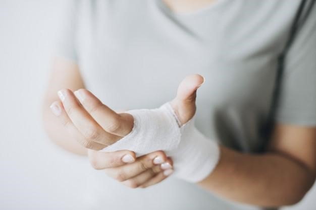 Young woman holding her hand that is wrapped in white medical dressing